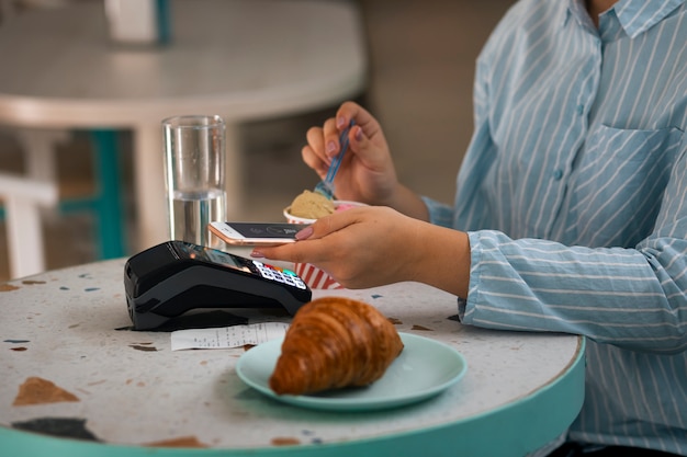 Foto gratuita persona que usa tecnología nfc para pagar en un restaurante