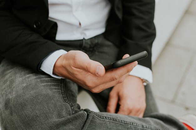 Persona que usa un teléfono inteligente para consultar las redes sociales mientras está sentado en el sofá