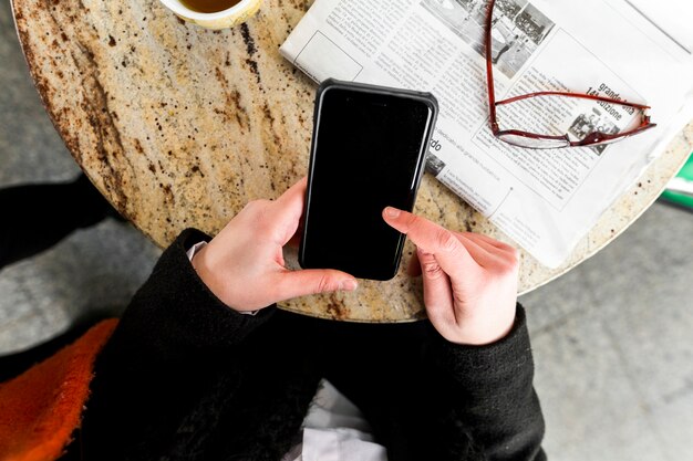 Persona que usa un teléfono inteligente en la mesa