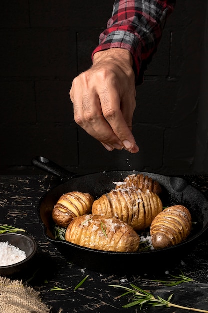 Foto gratuita persona rociando sal sobre papas en sartén