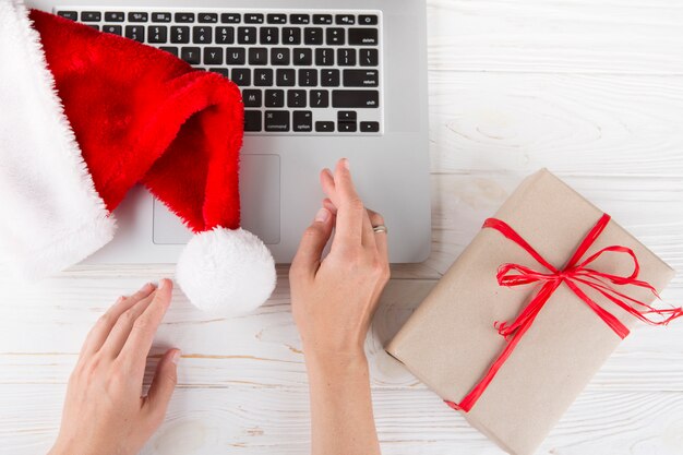 Persona sentada a la mesa con laptop y caja de regalo