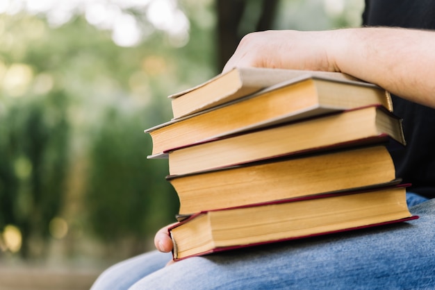 Foto gratuita persona sentada sosteniendo pila de libros