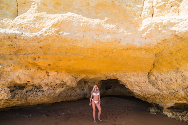 Foto gratuita persona de sexo femenino tomando el sol en la playa rocosa salvaje