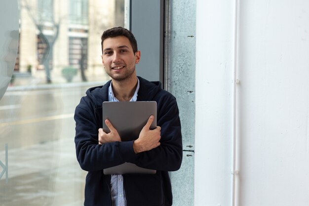 Una persona sonríe mientras sostiene la computadora portátil