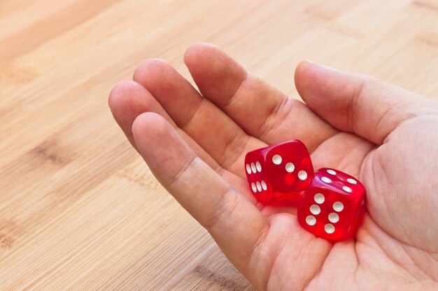Una persona sosteniendo dos dados rojos sobre una superficie de madera