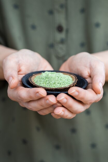 Persona sosteniendo un plato de polvo verde utilizado para alimentos crudos veganos