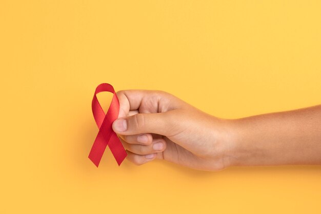 Persona sosteniendo un símbolo de cinta del día mundial del sida