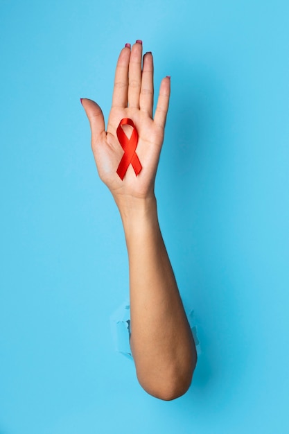 Persona sosteniendo un símbolo rojo del día mundial del sida