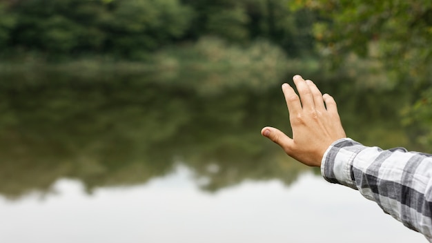 Persona sosteniendo su mano sobre el lago