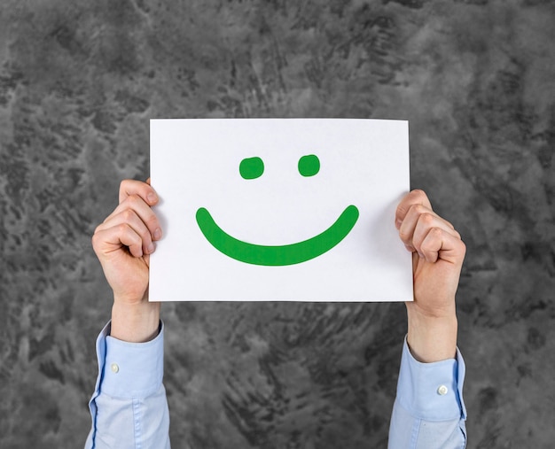 Persona sosteniendo una tarjeta con una carita sonriente