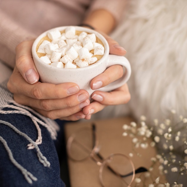 Persona sosteniendo una taza de chocolate caliente con malvaviscos