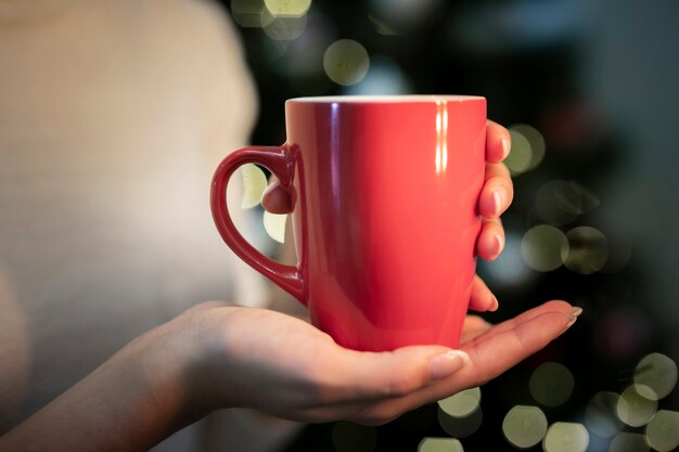 Persona sosteniendo una taza con fondo de Navidad