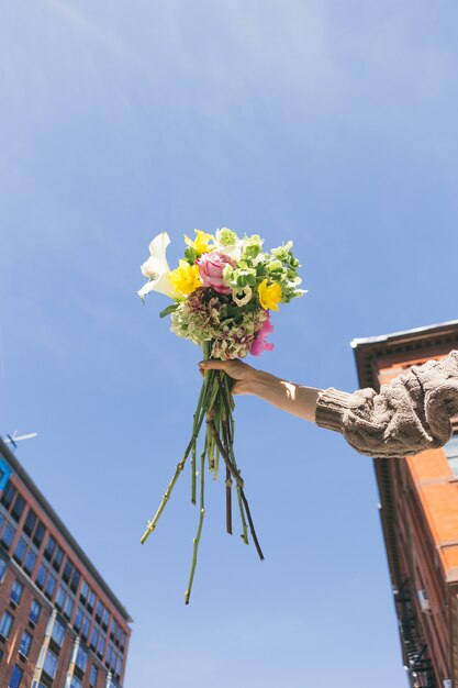 Persona en suéter de punto gris con ramo de flores