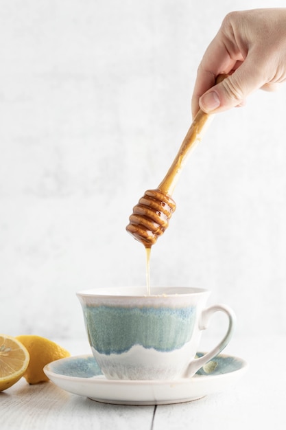 Persona sumergiendo miel en una taza de té