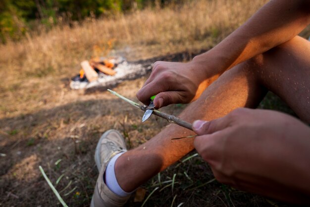 Persona talla un palo de madera al aire libre