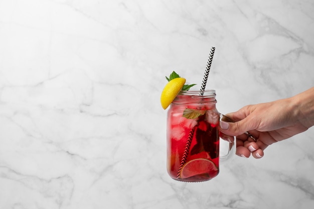 Foto gratuita persona con té helado de hibisco en un recipiente de vidrio transparente