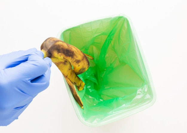 Persona tirando una cáscara de plátano en la papelera