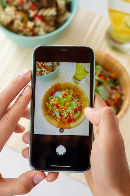 Foto gratuita persona tomando fotos de tazones con comida con teléfono inteligente