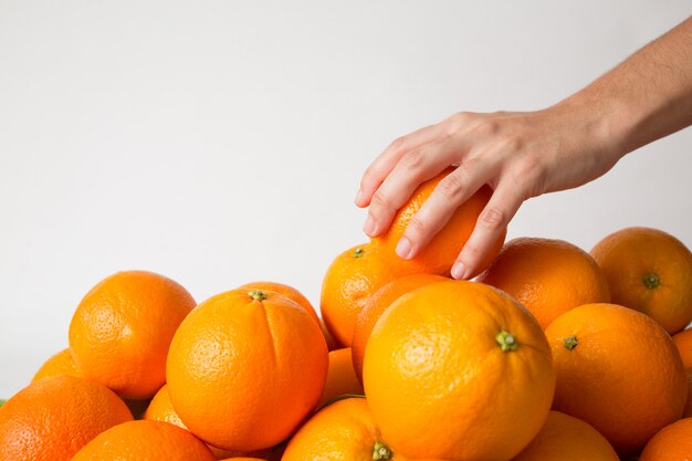 Persona tomando naranja del montón de frutas