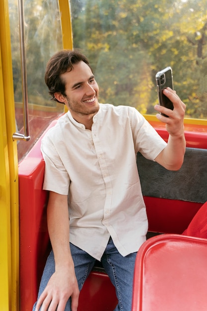 Foto gratuita persona tomando selfie con teléfono inteligente mientras está en la rueda de la fortuna