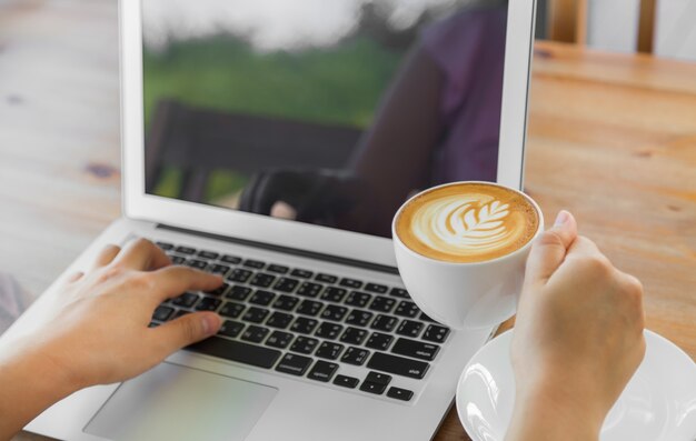 Persona trabajando en un portátil con una taza de café al lado