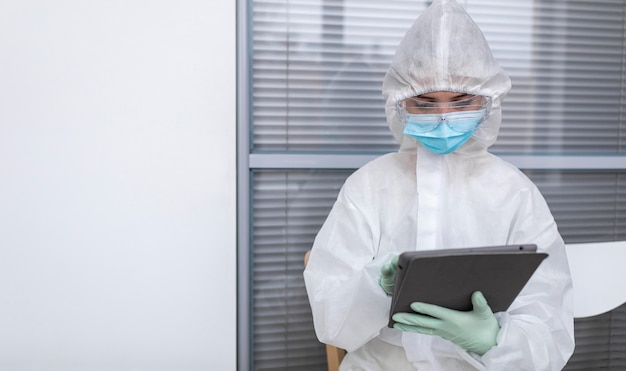 Persona en traje de protección mirando una tableta