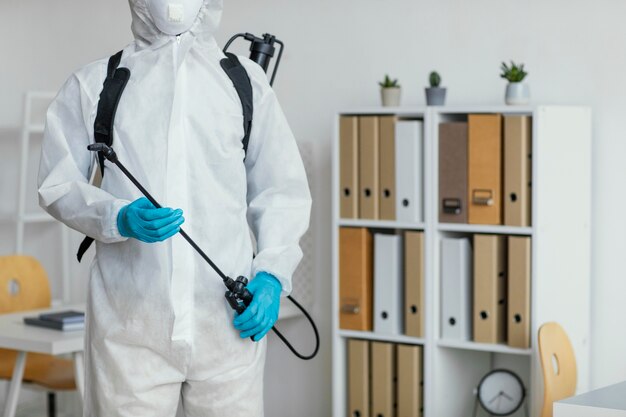 Persona en traje de protección preparándose para desinfectar una habitación