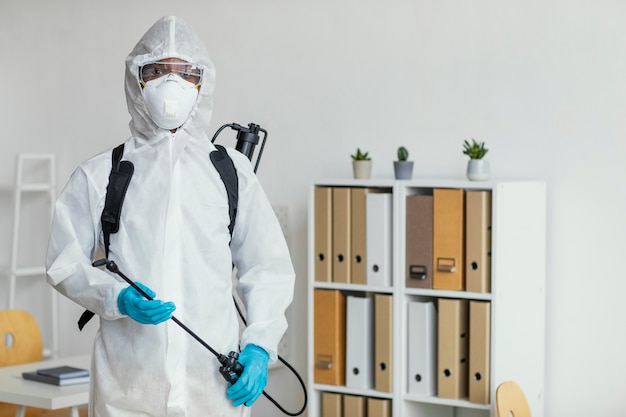 Persona en traje de protección preparándose para desinfectar una habitación