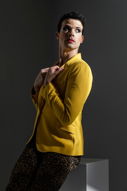 Persona transgénero vistiendo chaqueta amarilla de pie hacia los lados