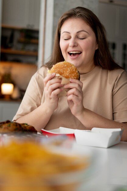 Persona con trastorno alimentario tratando de comer comida rápida.