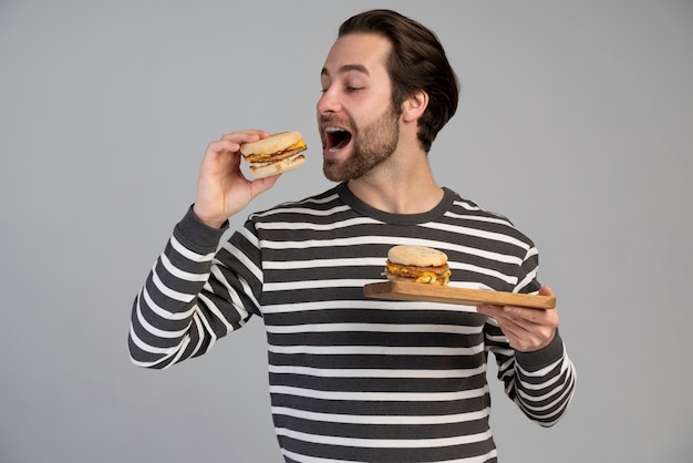 Foto gratuita persona con trastorno alimentario tratando de comer comida rápida.