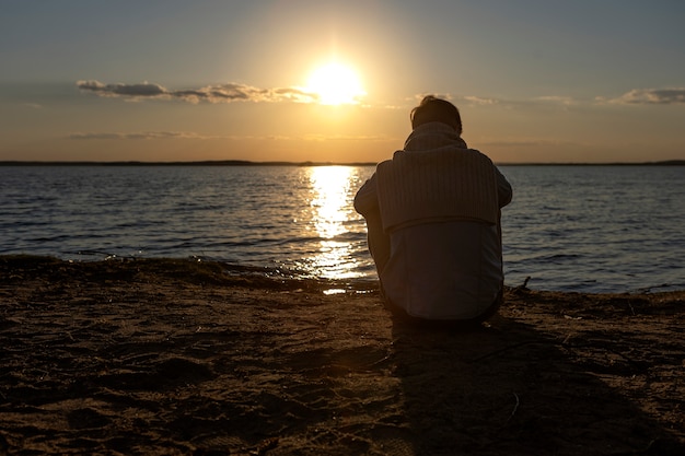 Persona triste y contemplativa cerca del lago.