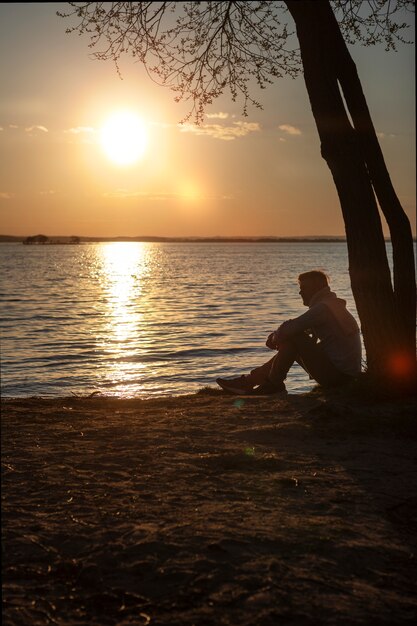 Persona triste y contemplativa cerca del lago.