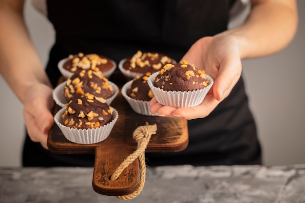 Persona de vista frontal sosteniendo cupcakes dulces