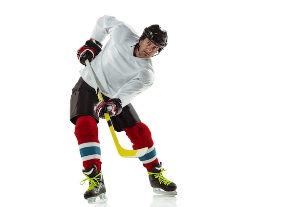 Foto gratuita personaje. jugador de hockey masculino joven con el palo en la cancha de hielo y pared blanca. deportista con equipo y casco practicando. concepto de deporte, estilo de vida saludable, movimiento, movimiento, acción.