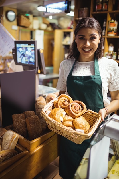 Personal femenino con croissant en cesta de mimbre en mostrador de pan