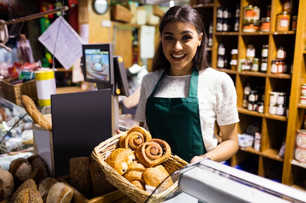 Personal femenino con croissant en cesta de mimbre en mostrador de pan