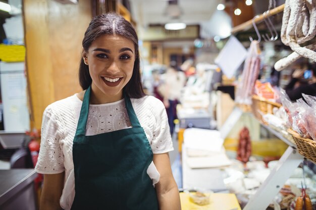 Personal femenino de pie en el mostrador de carne