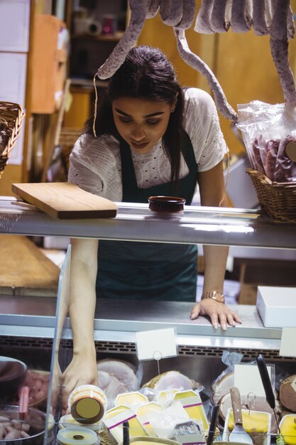 Personal femenino que trabaja en el mostrador de carne