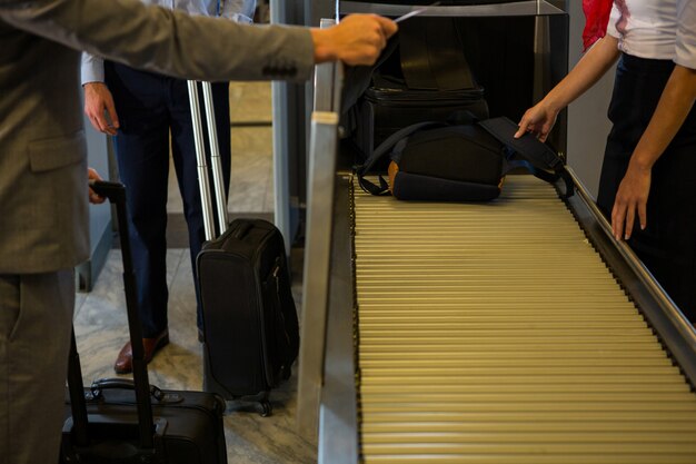 Personal femenino revisando el equipaje de los pasajeros en la cinta transportadora