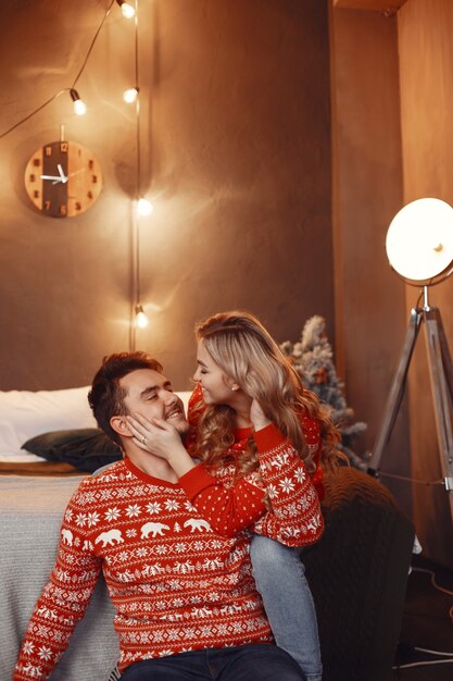 Personas en adornos navideños. Hombre y mujer con un suéter rojo.