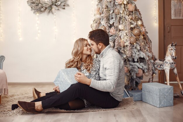 Personas en adornos navideños. Hombre con un suéter gris. Familia en casa.