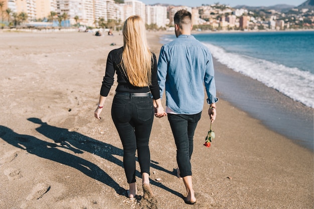 Personas amorosas tomados de la mano caminando en la playa