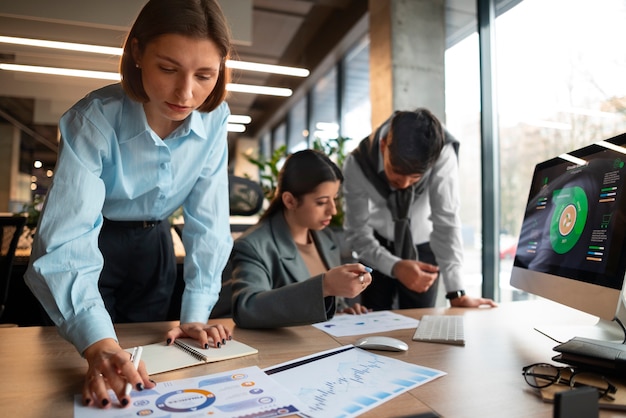 Foto gratuita personas analizando y revisando gráficos financieros en la oficina