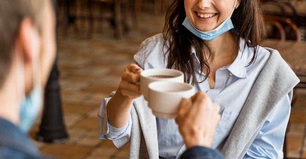 Personas animando con sus tazas de té mientras usan mascarillas en la barbilla