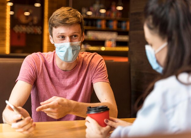 Personas charlando mientras usan máscaras médicas en el interior