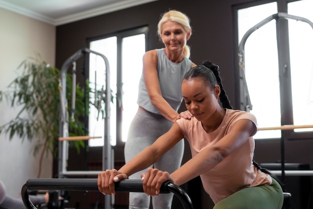 Foto gratuita personas en clase reformadora de pilates ejercitando sus cuerpos