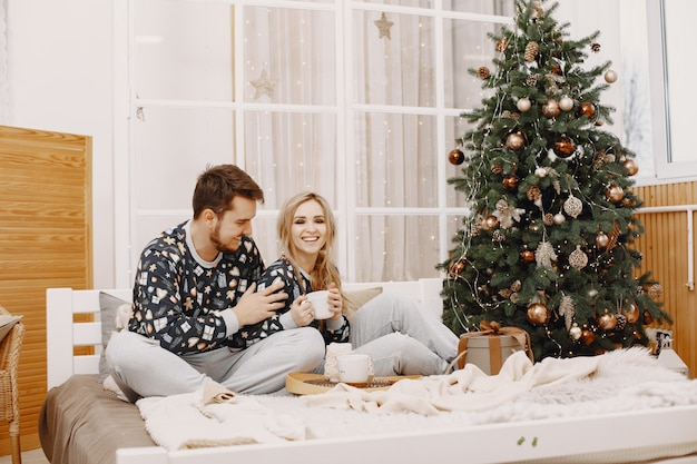 Personas en decoraciones de Christman. Hombre y mujer en pijama identifical. Familia en una cama.