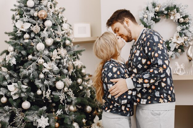 Personas en decoraciones de Christman. Hombre y mujer en pijama identifical. Familia en casa.