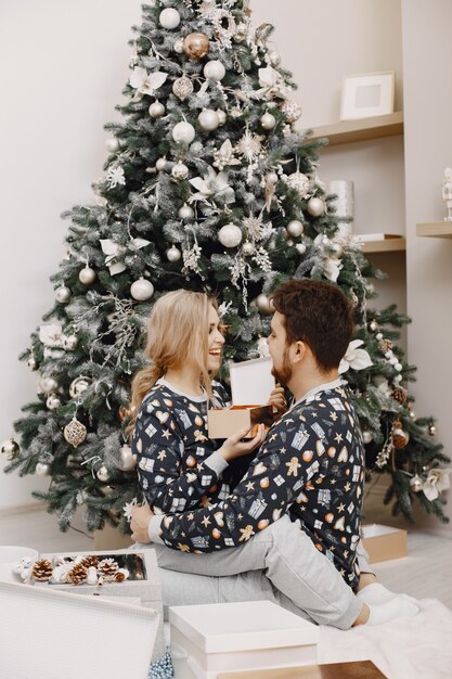 Personas en decoraciones de Christman. Hombre y mujer en pijama identifical. Familia en casa.